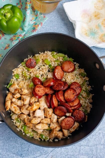 Browning chicken and andouille sausage in a skillet.
