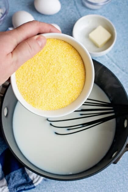 Adding cornmeal to a pot of milk for Southern spoonbread recipe.