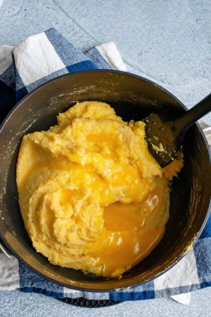 Adding egg yolks to Southern spoonbread batter in a mixing bowl.