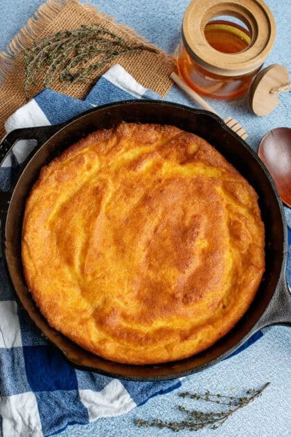 Beautifully golden Southern spoonbread in a cast iron skillet fresh out the oven.