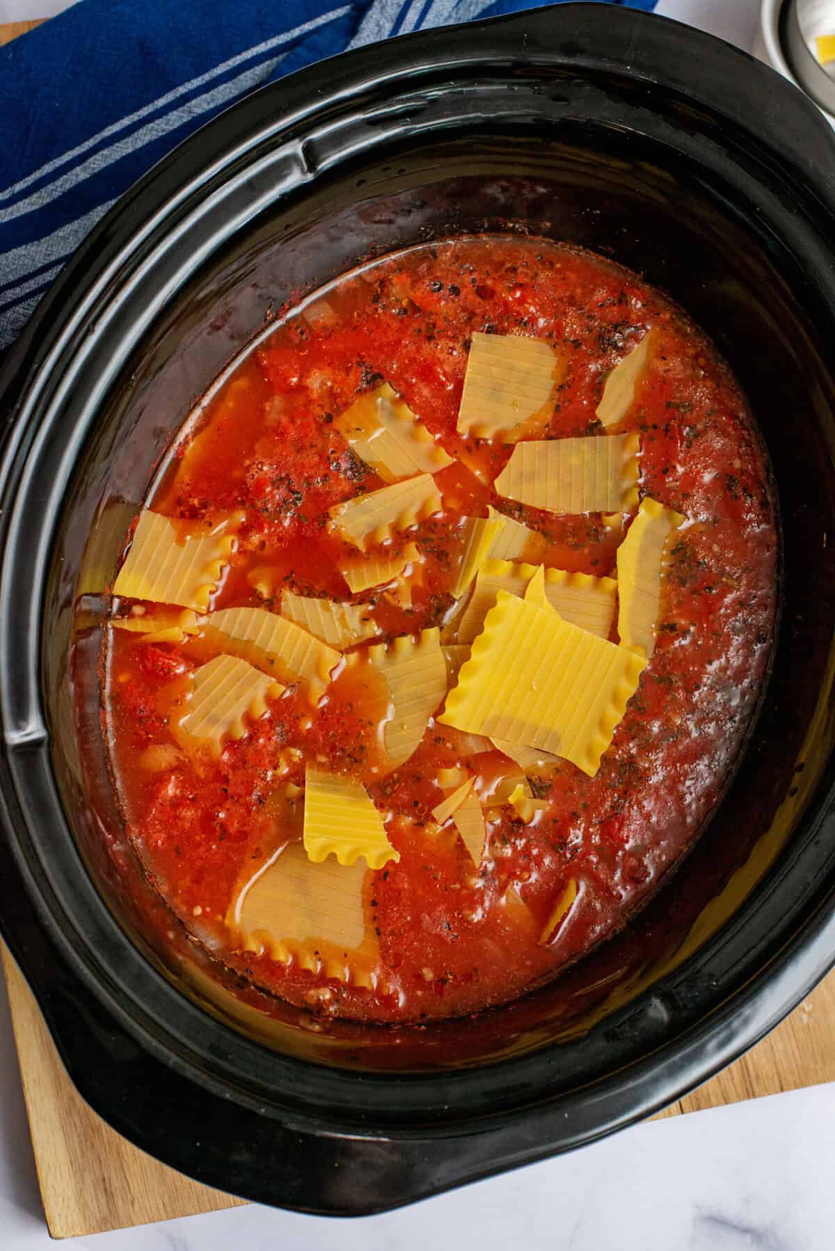 Adding broken lasagna noodles to crockpot lasagna soup.