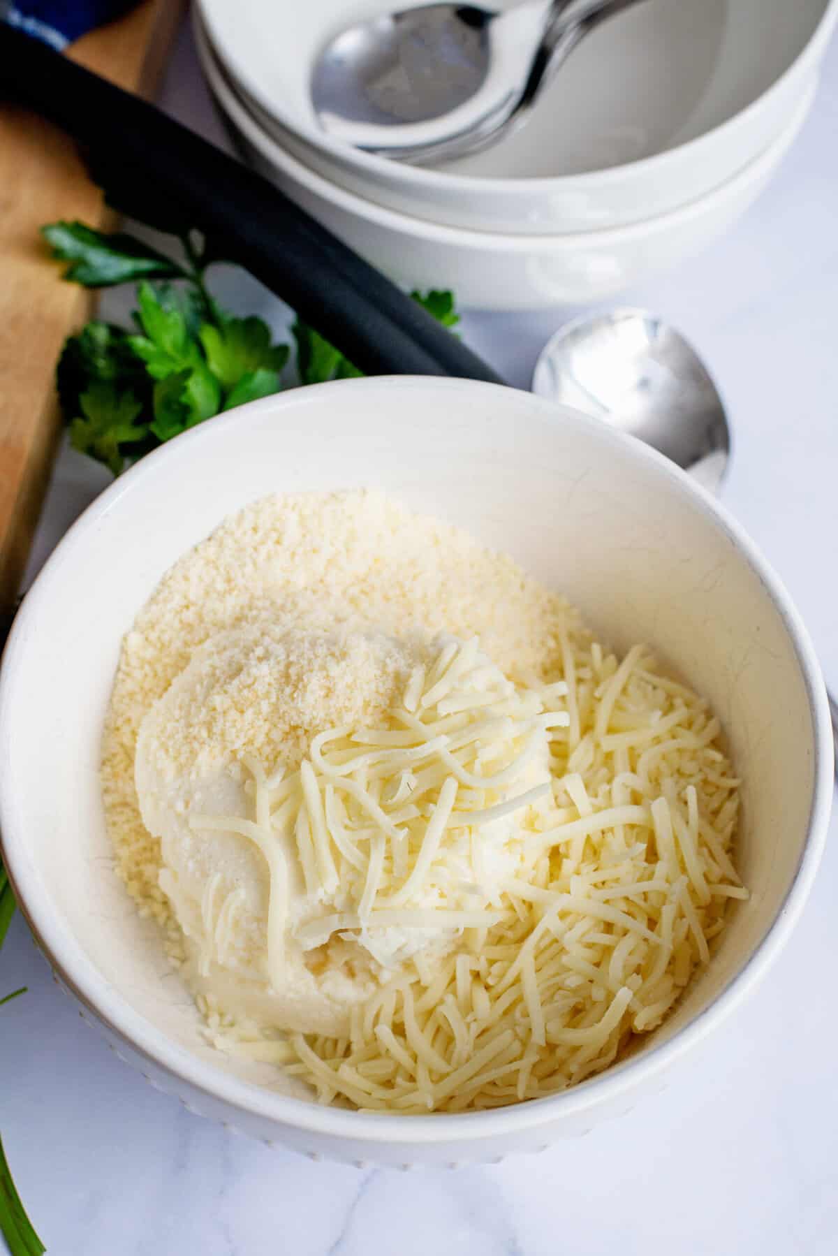 Parmesan, mozzarella, and ricotta cheese in a white bowl.