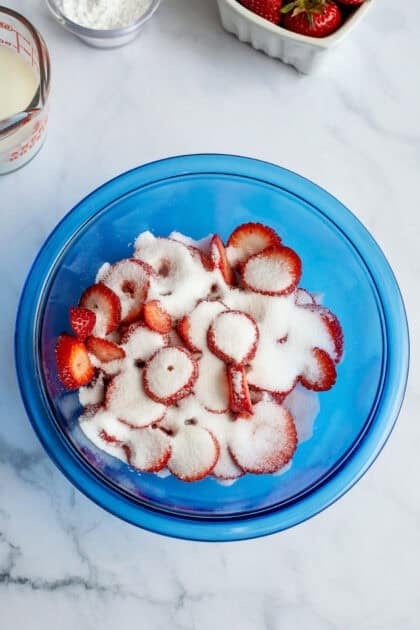 Strawberries and sugar in a mixing bowl.