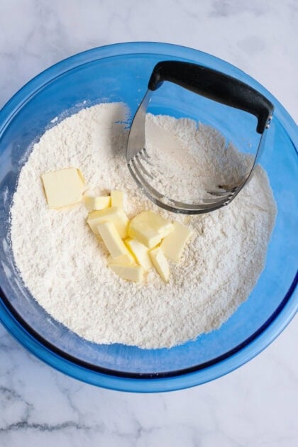Adding butter to a bowl of flour.
