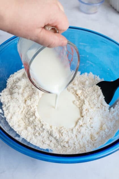 Adding buttermilk to a mixing bowl of dry ingredients.