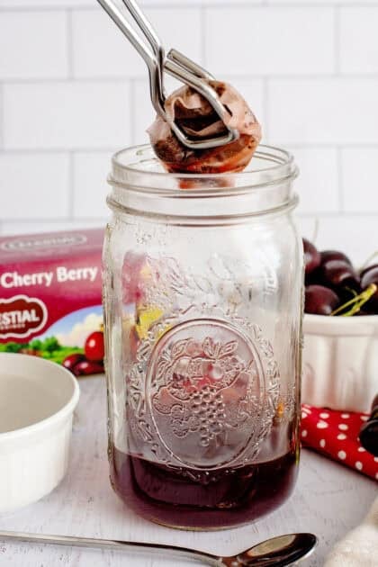 Removing seeped tea bags from mason jar with tongs