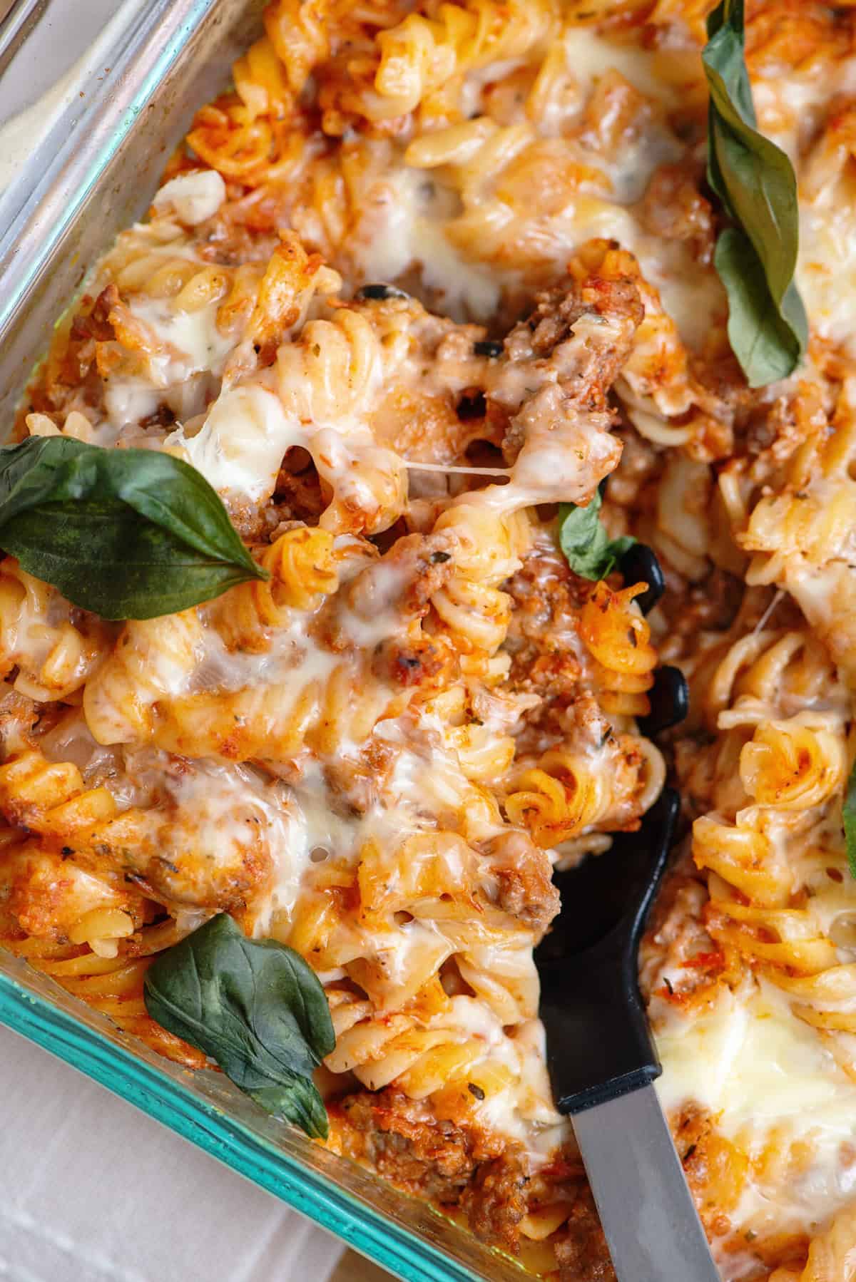 Close-up of a spoon scooping out a serving of Italian pasta bake.