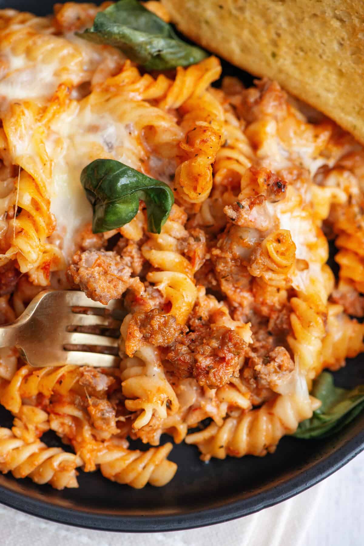 Schließen Sie die Gabel, die in einer italienischen Pasta mit frischem Basilikum kocht.