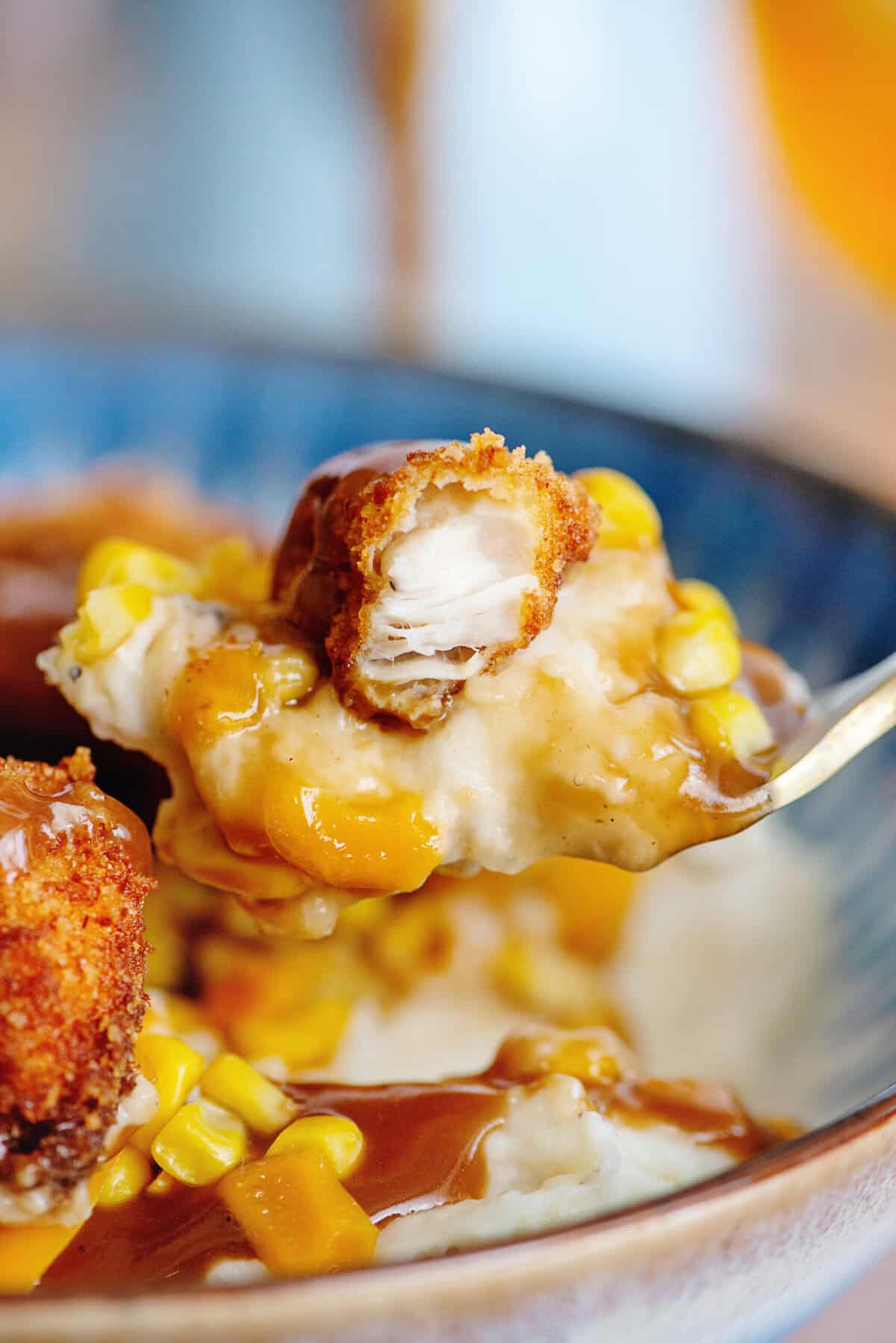 A heaping spoonful of mashed potatoes, chicken, corn, and gravy.
