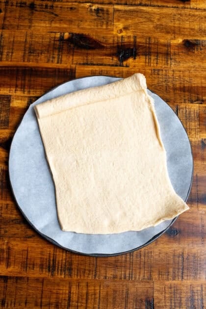 Rolling out crescent roll dough on a wooden table.