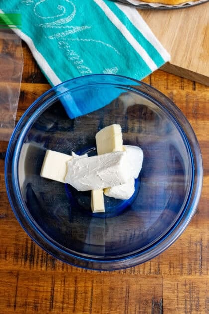 Butter and cream cheese in a blue mixing bowl to make cream cheese icing.