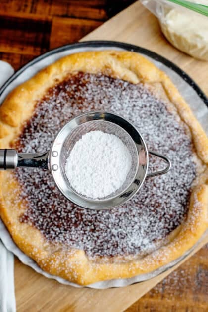 Dusting powdered sugar onto a dessert pizza.