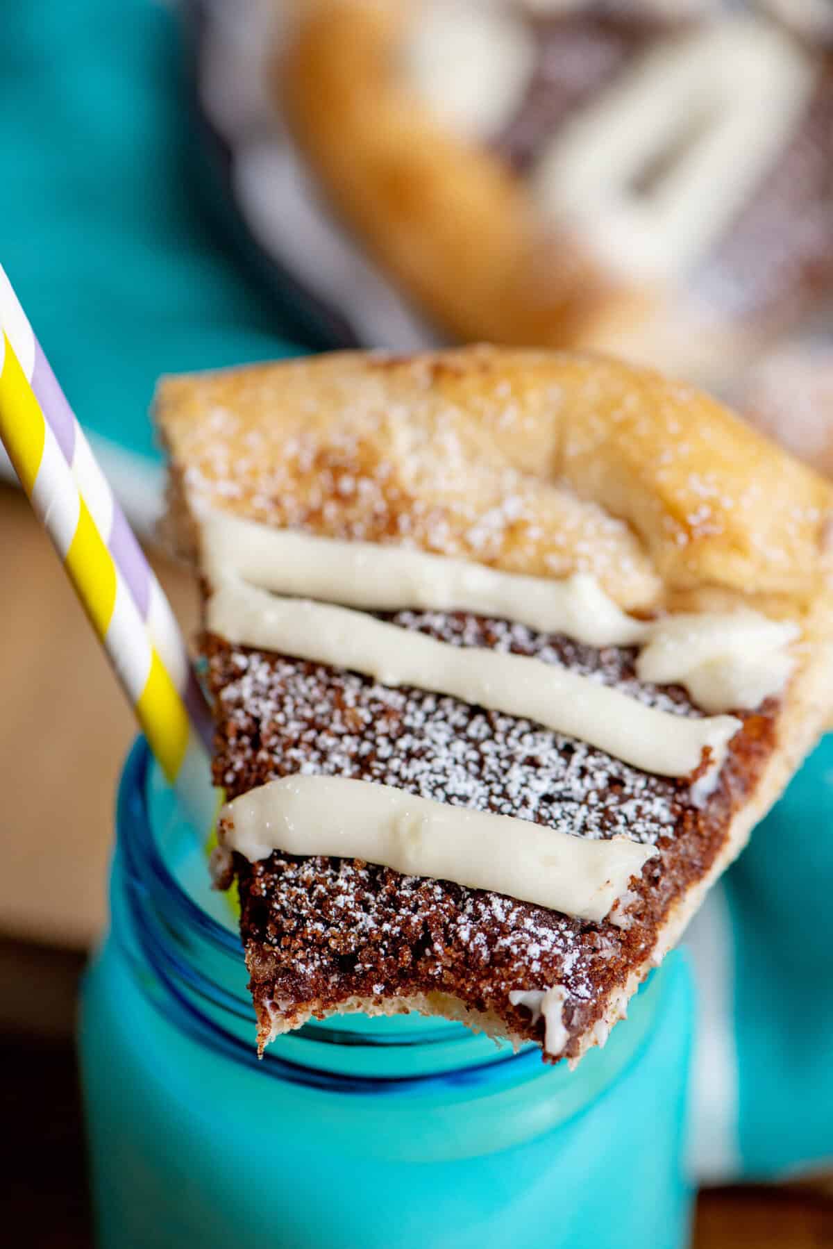 Close-up of a slice of cinnamon sugar dessert pizza resting on a turquoise mason jar of milk.