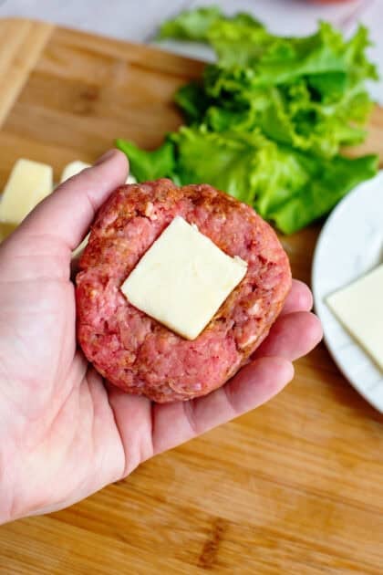 Cheeseburger patty with square of butter in the middle