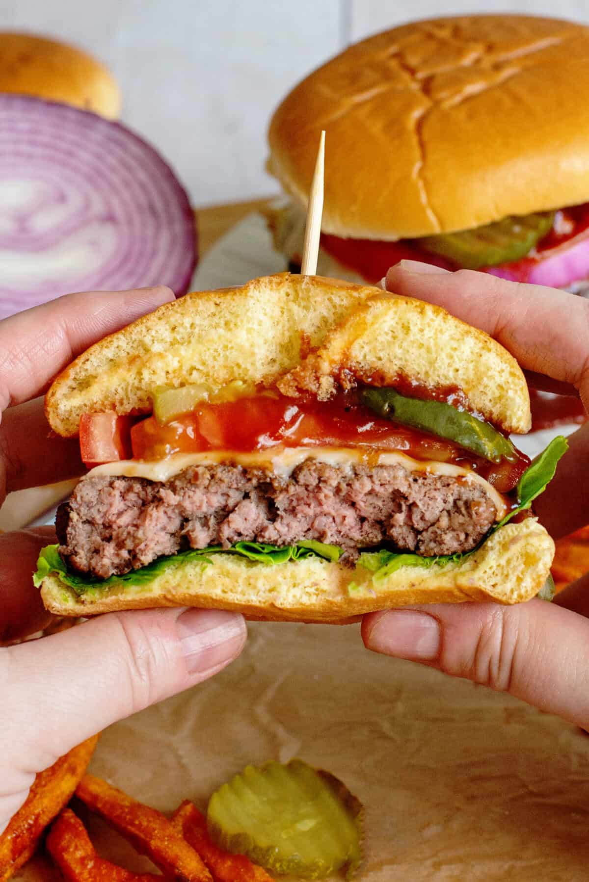 Person holding an assembled southern grilled cheeseburger with a bite taken out