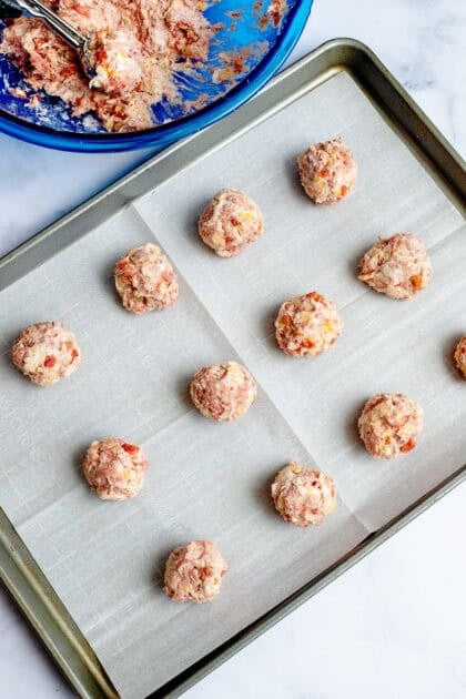 Rotel cream cheese sausage balls lined up on a baking sheet