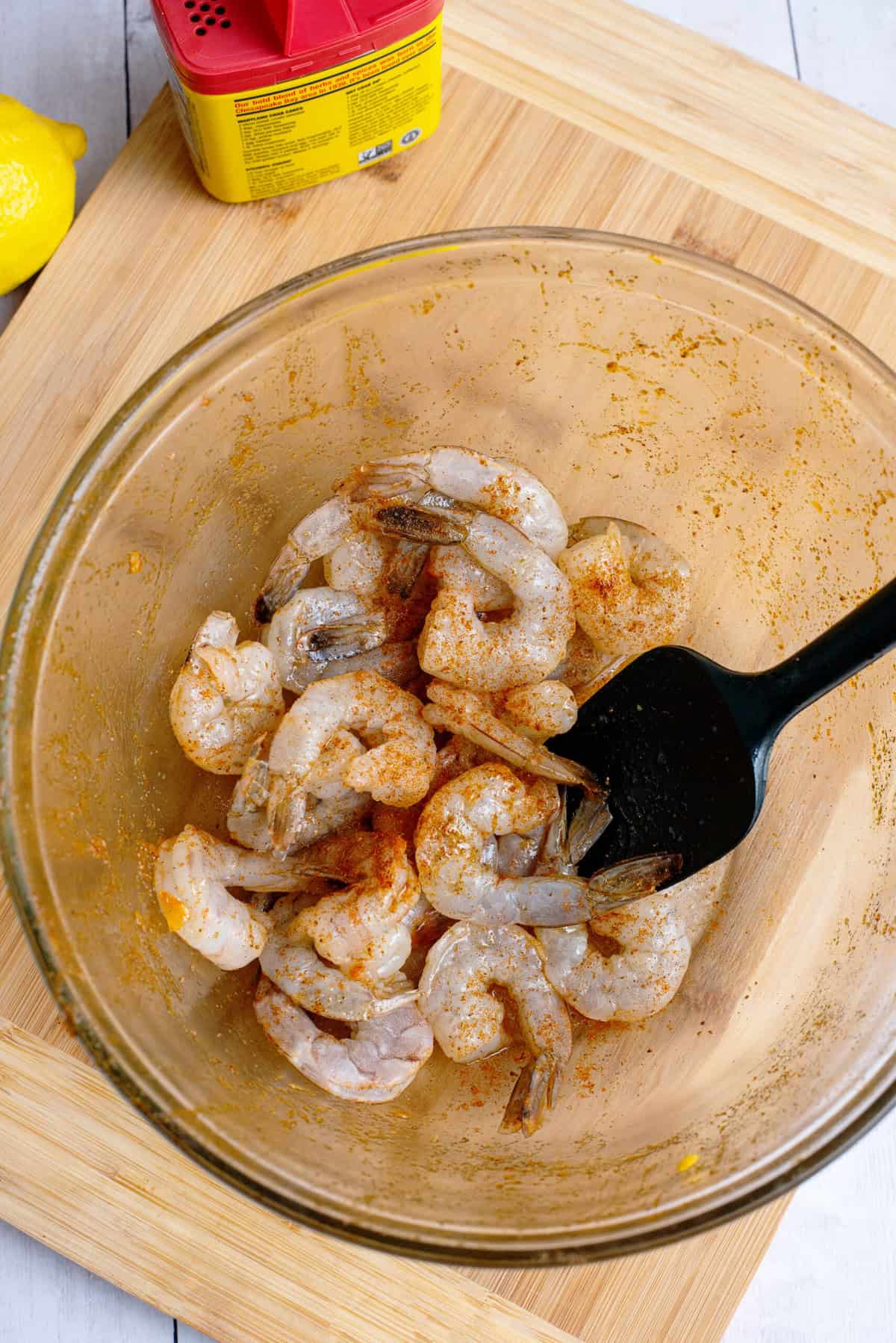 Raw shrimp in bowl being prepped with butter and seasoning
