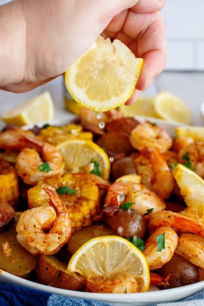 Seafood boil on individual plate with lemon being squeezed on it
