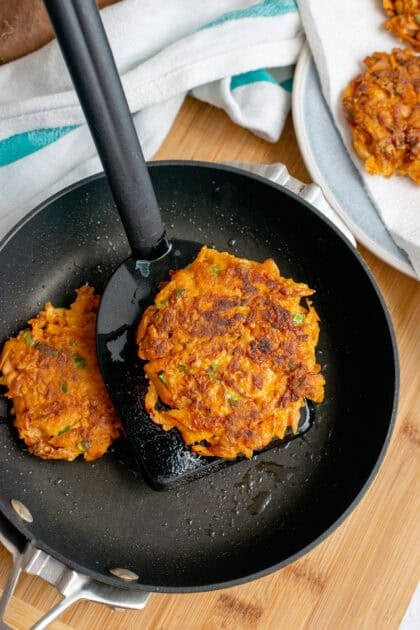 Sweet potato fritters being cooked in the large skillet