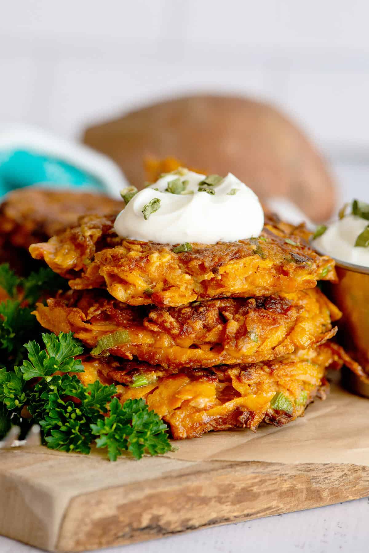 A stack of sweet potato fritters with sour cream on top