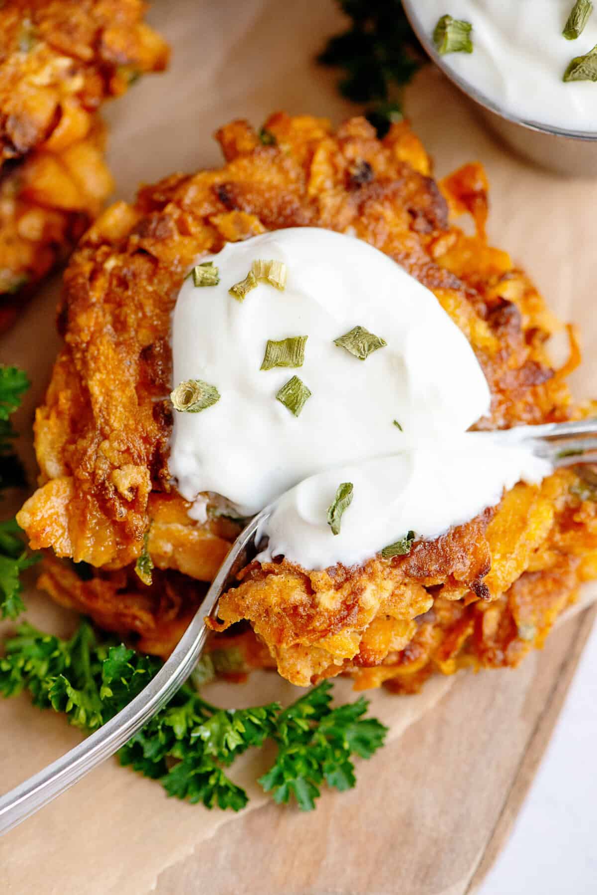 A fork cutting into a sweet potato fritter with toppings