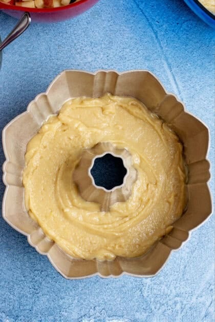 Half of the apple pound cake batter in a bundt pan