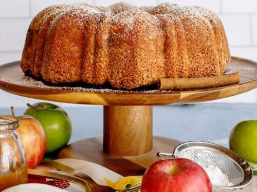 Rustic apple pound cake on a serving tray with apples under it
