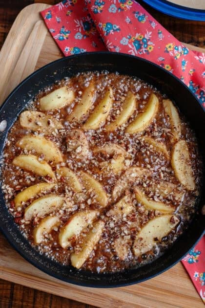 Pecans sprinkled on top of apple slices in a skillet