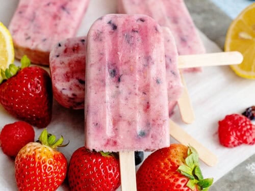 A plate of berries and cream popsicles with fruits on the plate