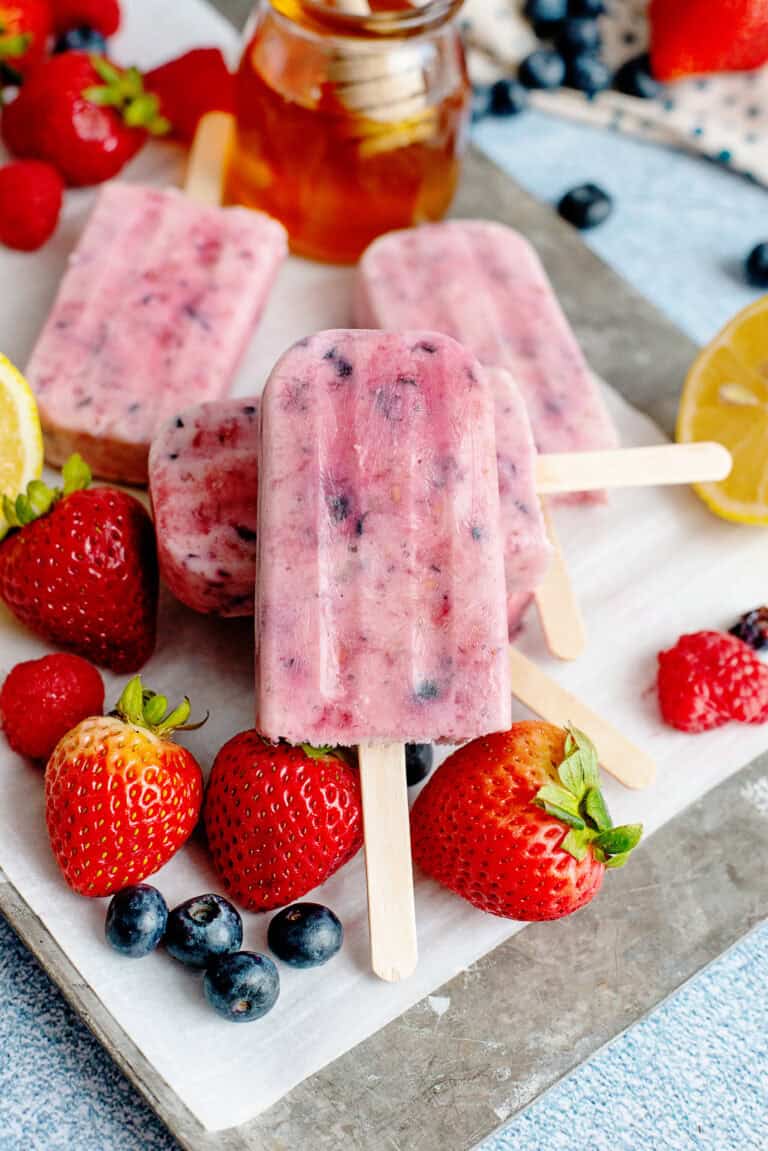 A plate of berries and cream popsicles with fruits on the plate