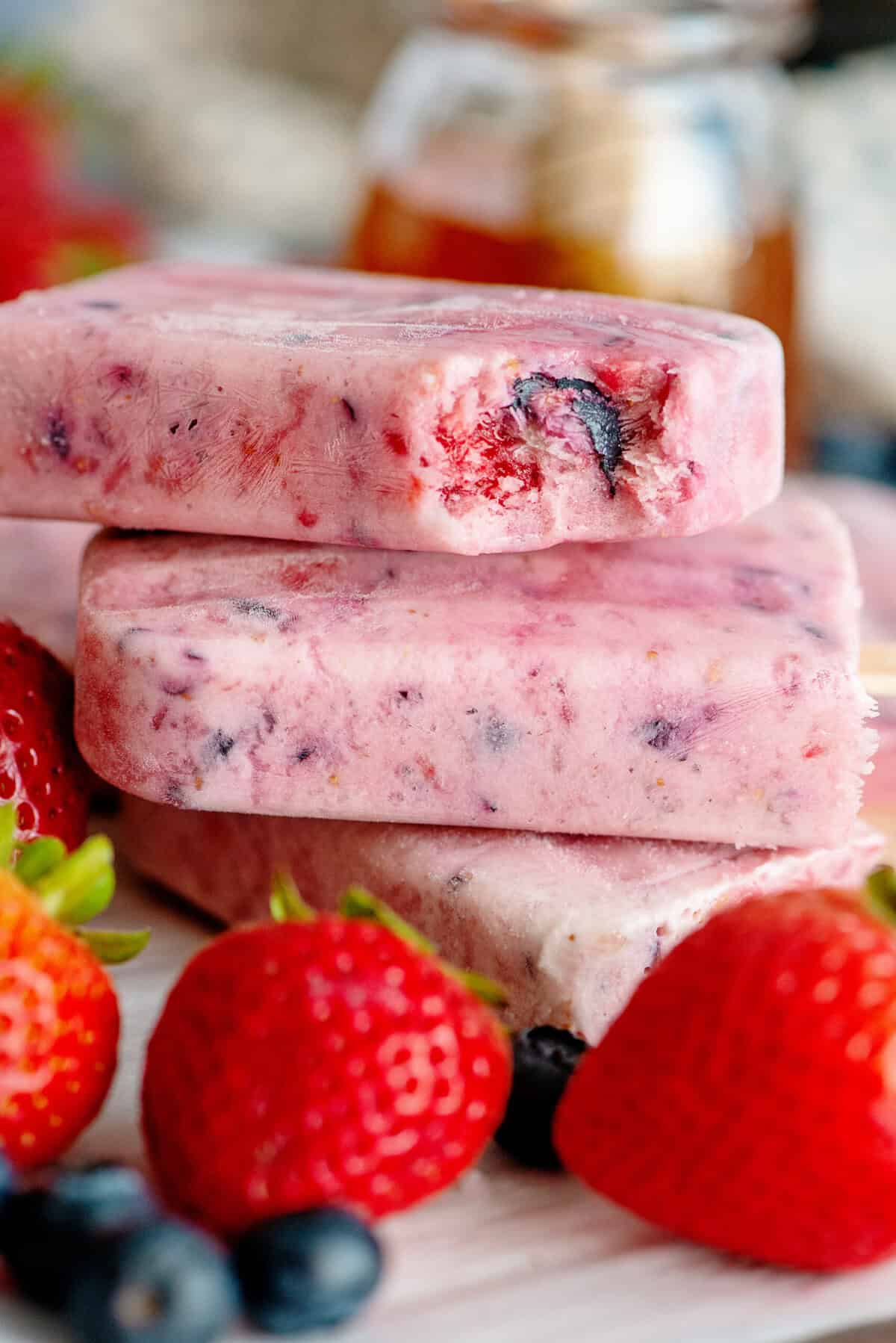 close up of berries and cream popsicles stacked on each other