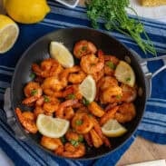 A pan of cajun shrimp with lemon wedges