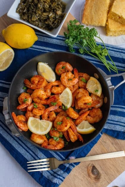 A pan of cajun shrimp with lemon wedges