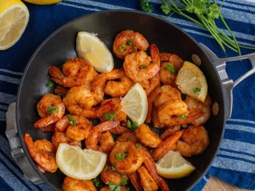 A pan of cajun shrimp with lemon wedges