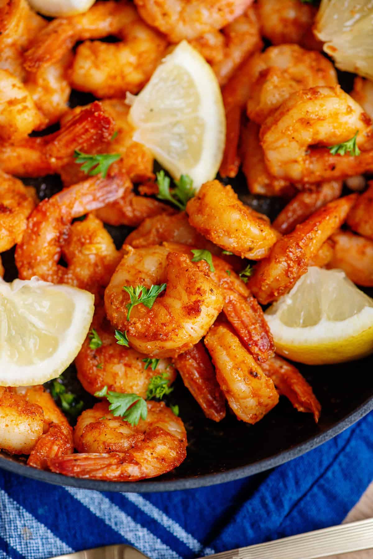 Close up of cajun shrimp on a plate with lemon wedges
