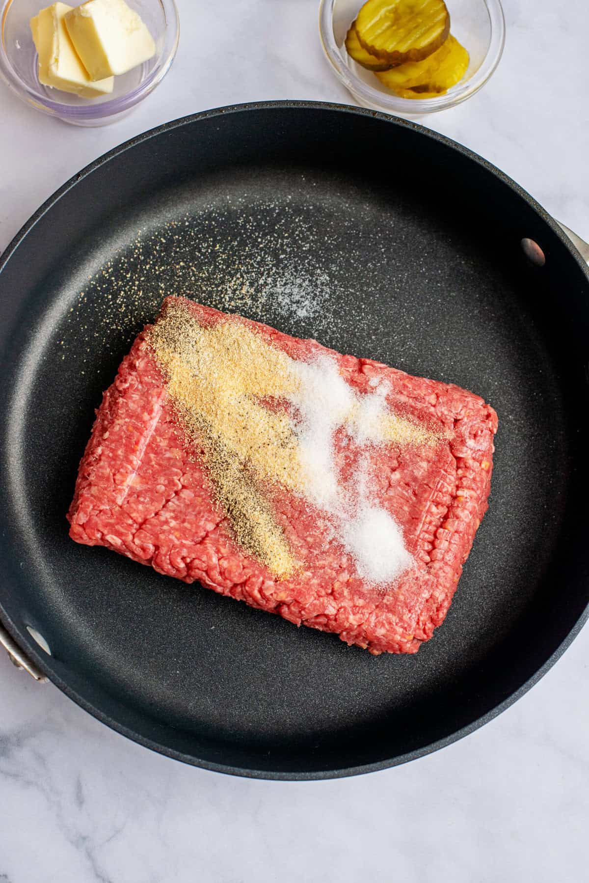 ground beef being cooked in skillet witg salt, black pepper, garlic powder, and onion powder