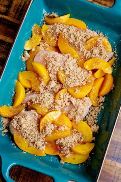 Sliced peaches and brown sugar mixture being placed on the chicken