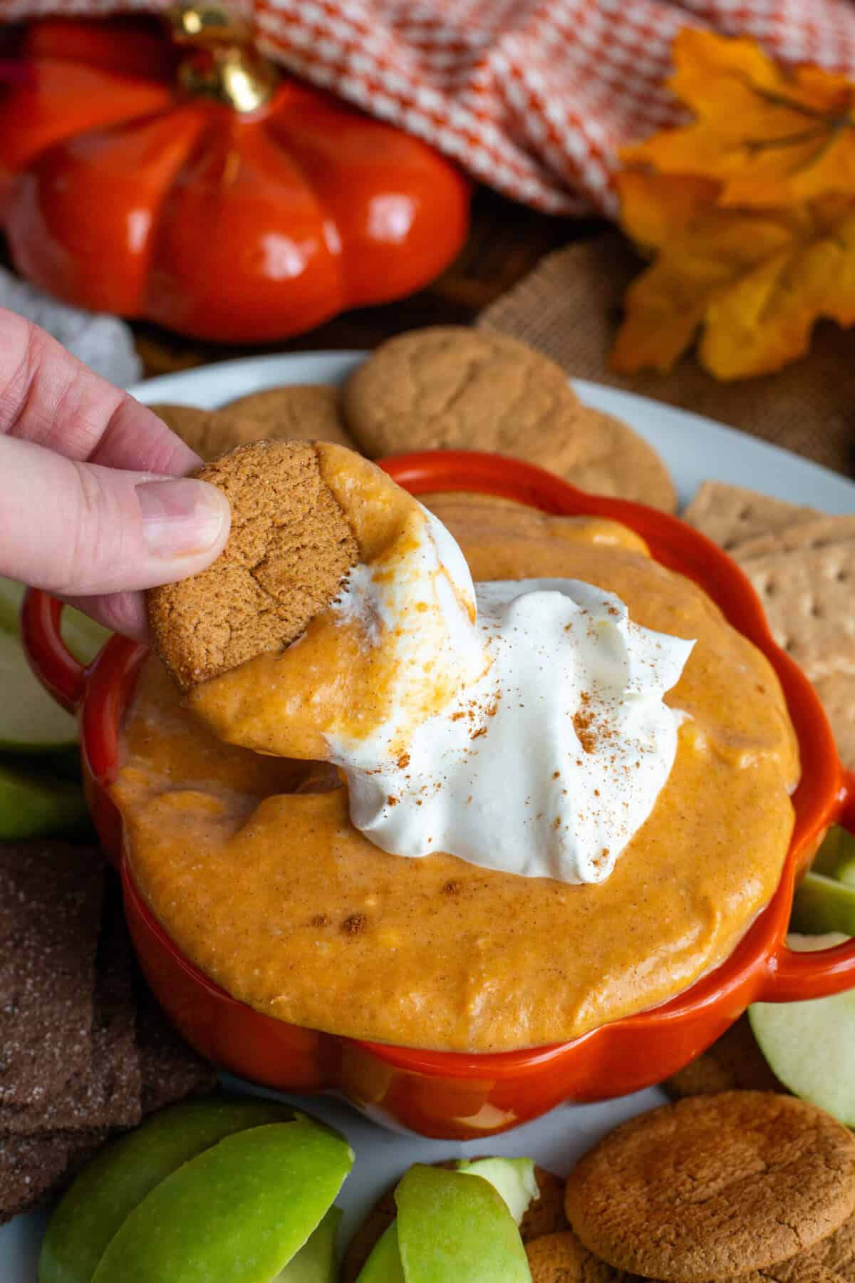 A hand dipping into pumpkin pie dip.