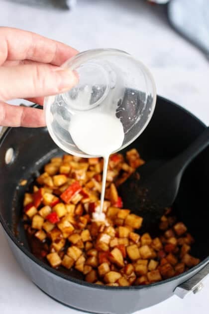 pouring cornstarch into a skillet of apple filling