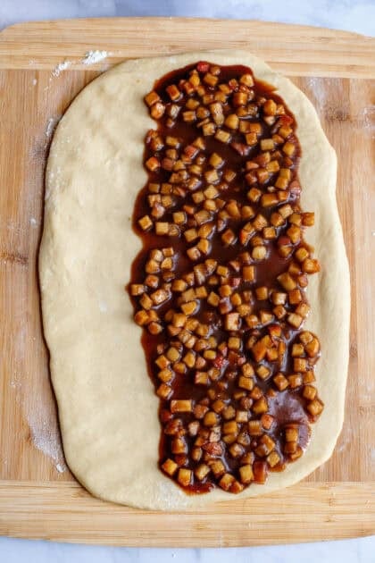 Apple filling spread across the apple cinnamon roll dough