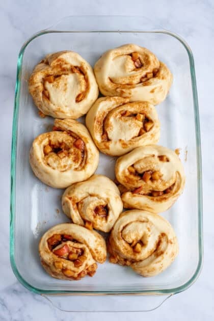 Sliced apple cinnamon rolls in a baking sheet after rising