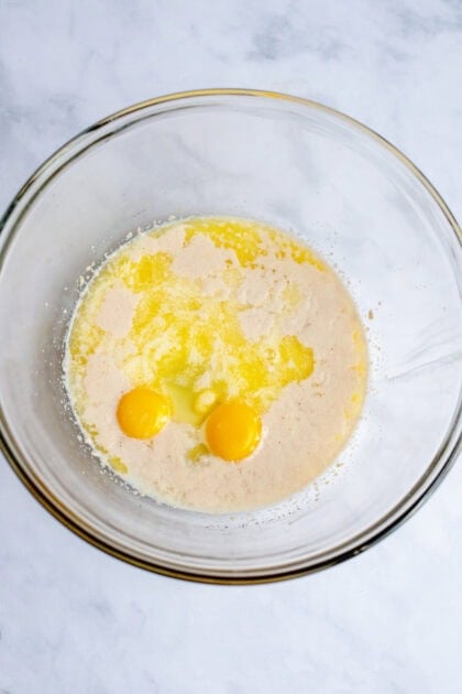 A mixing bowl of dry ingredients for apple cinnamon rolls with egg mixed in