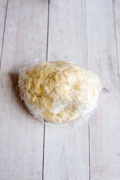 A ball of fried apple hand pie dough in plastic wrap