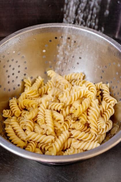 Cooked pasta being drained in a strainer
