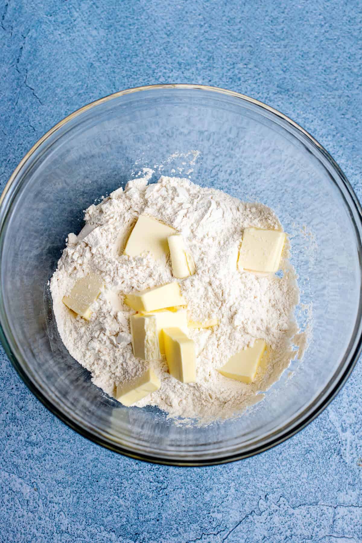 A large bowl of self-rising flour and cold butter slices