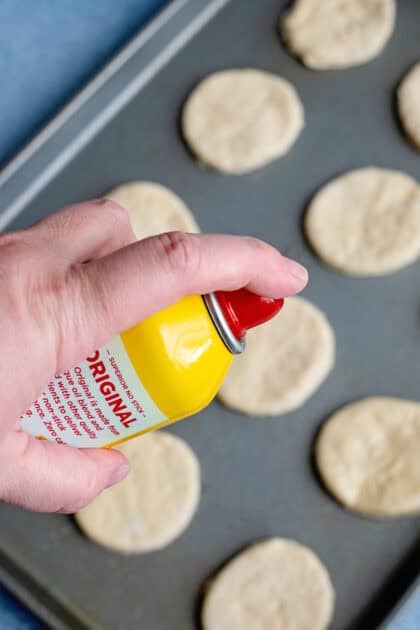 Spraying the tops of the easy homemade biscuits with cooking spray