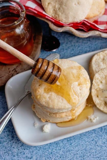 A plate of easy homemade biscuits being drizzled with honey