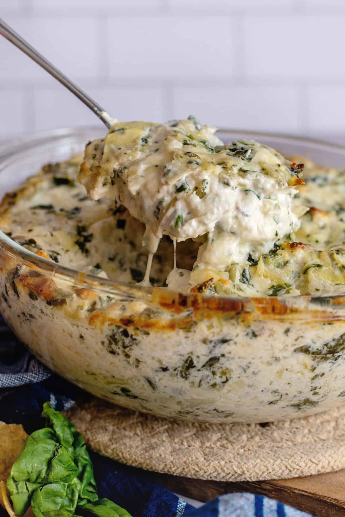 Taking a spoonful of spinach artichoke dip from a bowl