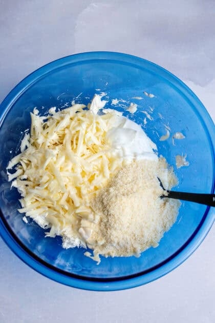 A bowl with cream cheese, sour cream, mayo, and cheese