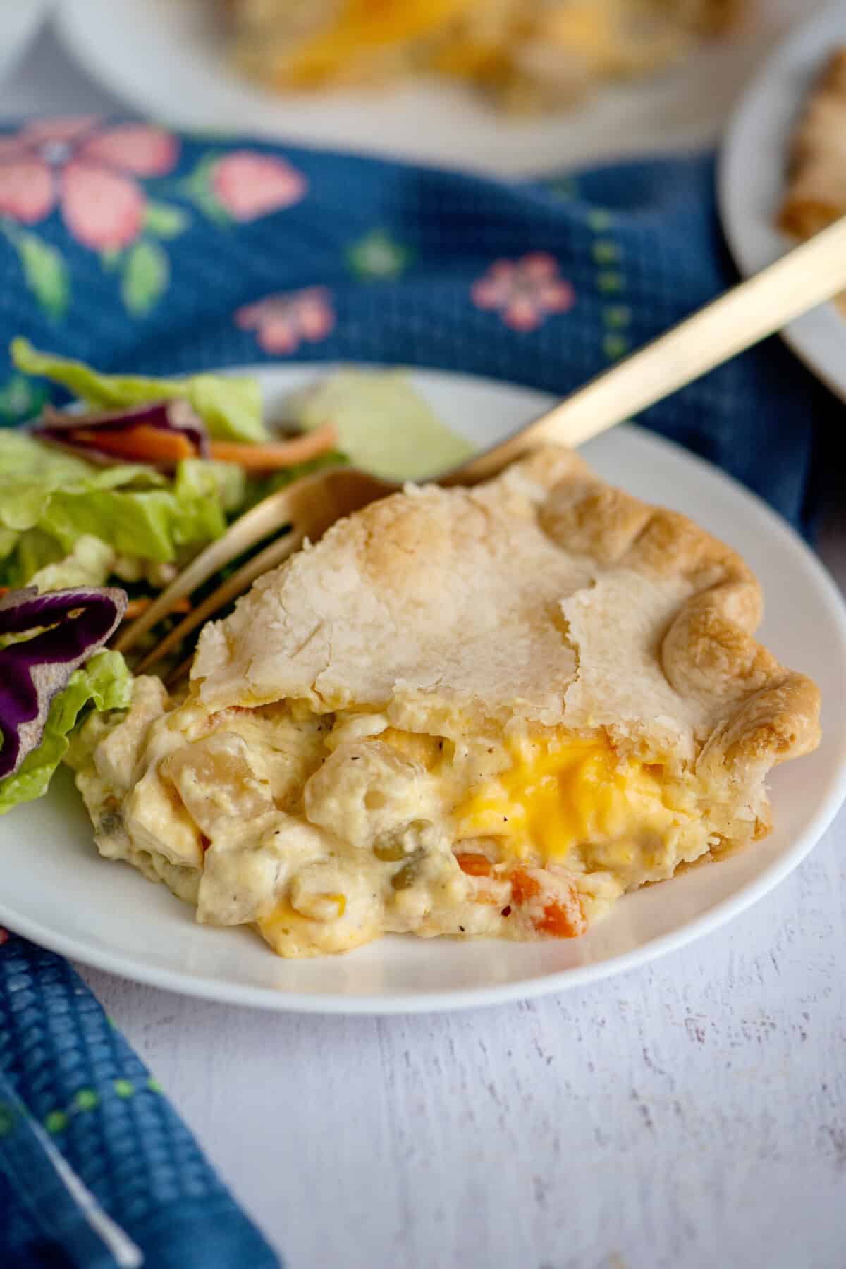 A plate of cheesy chicken pot pie being eaten with a fork